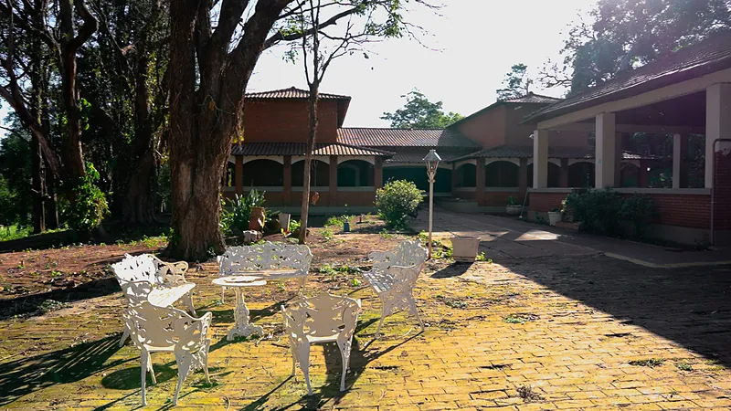 Jardim do Instituto Ágape com mesas e cadeiras brancas sob as árvores